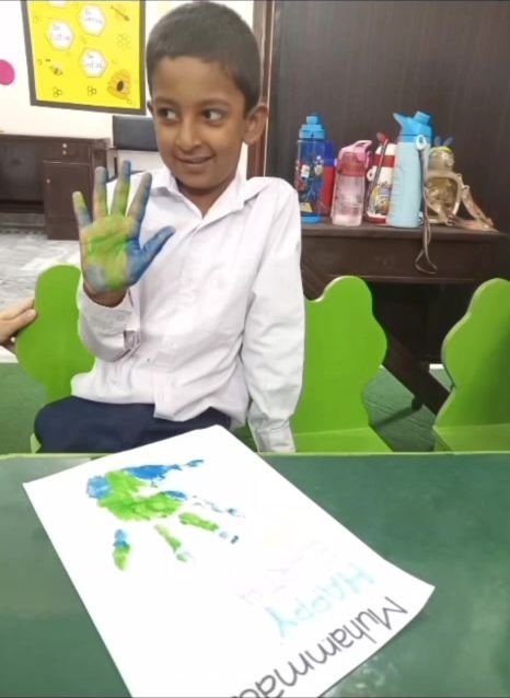 Student showing painted hand after making Earth Day artwork
