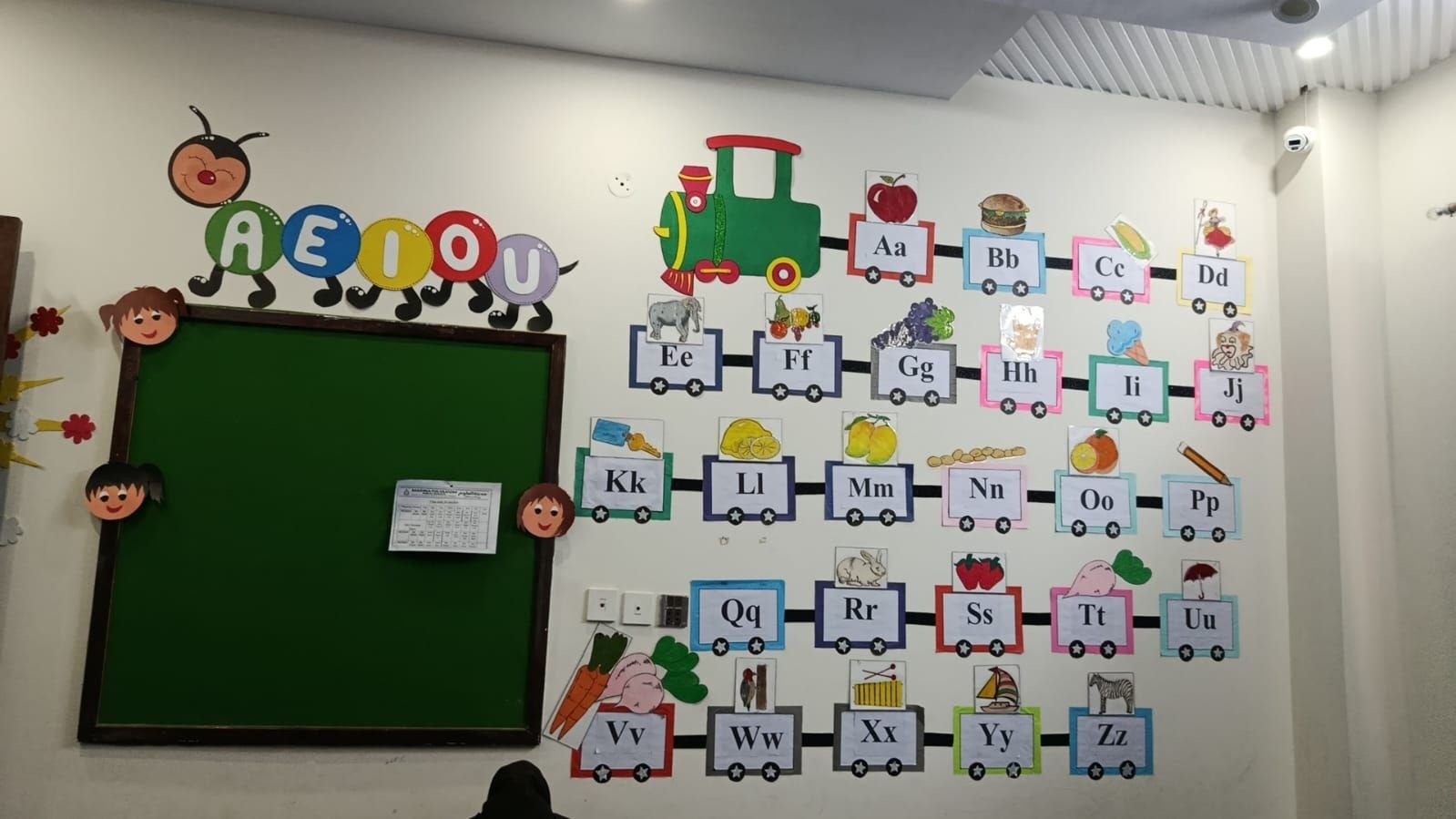 Classroom wall with alphabet display and ceiling-mounted CCTV camera